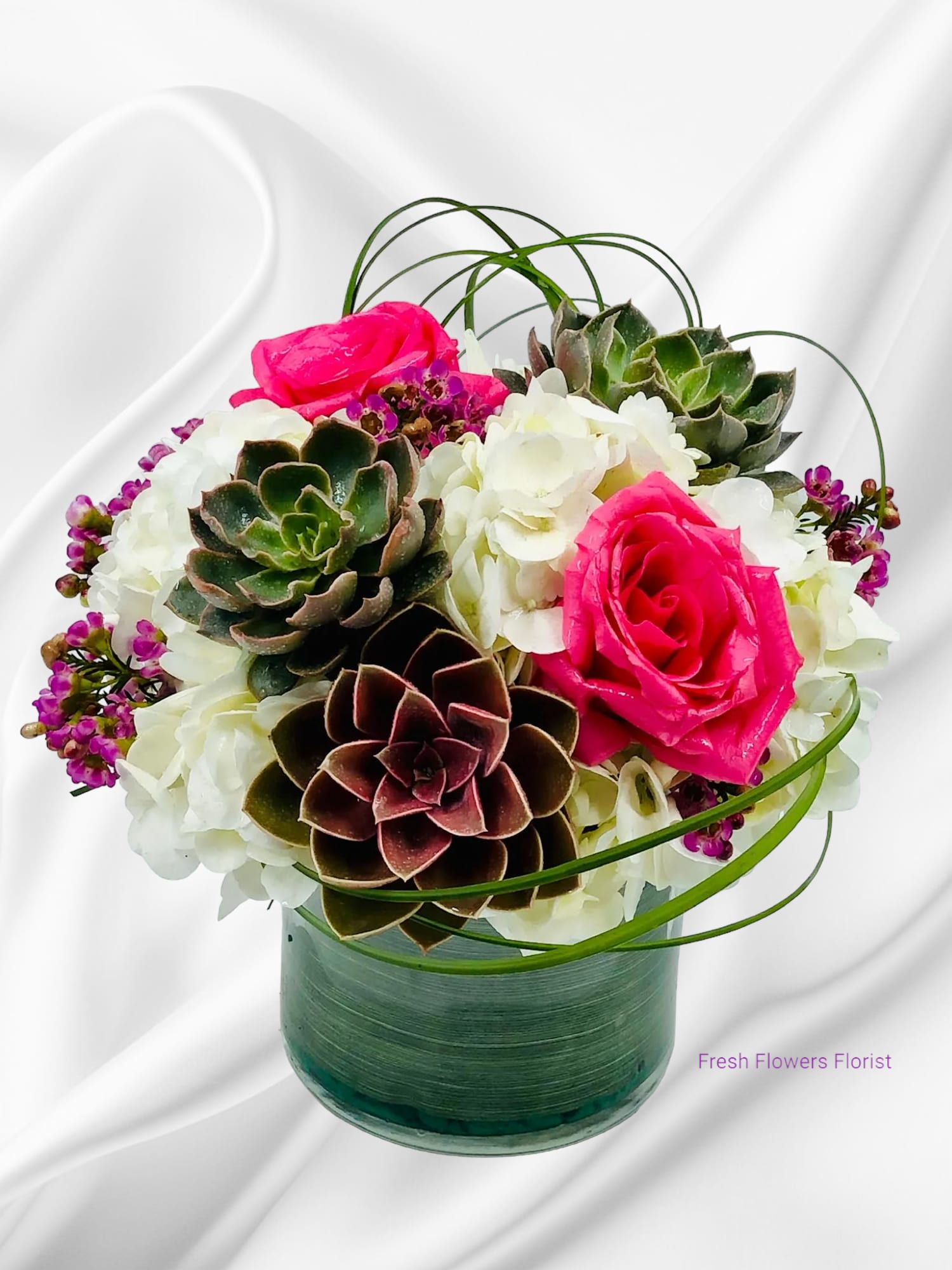 Pink roses and white hydrangeas with succulents in a glass vase