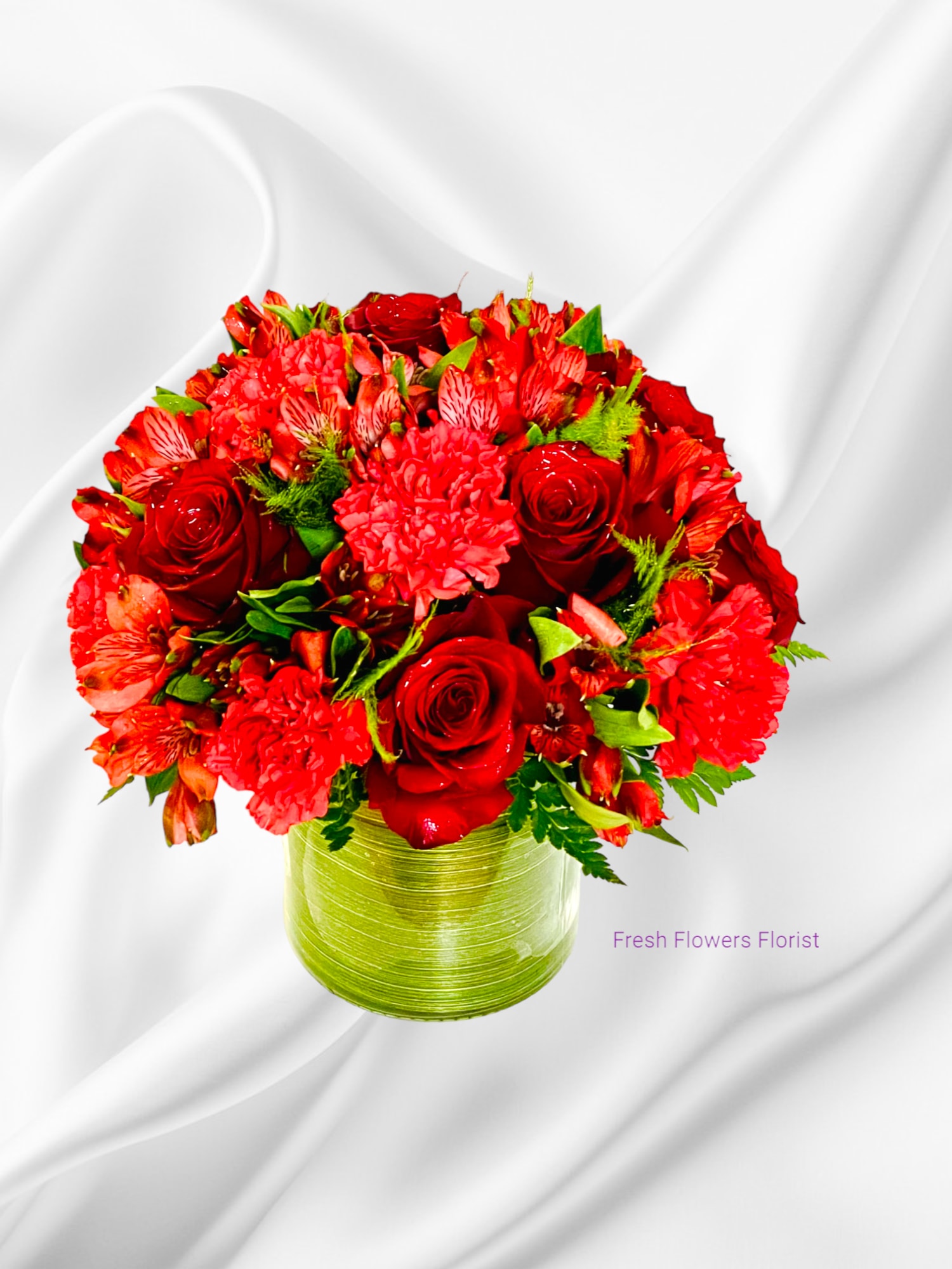 Red roses and mixed red flowers arranged in a green vase