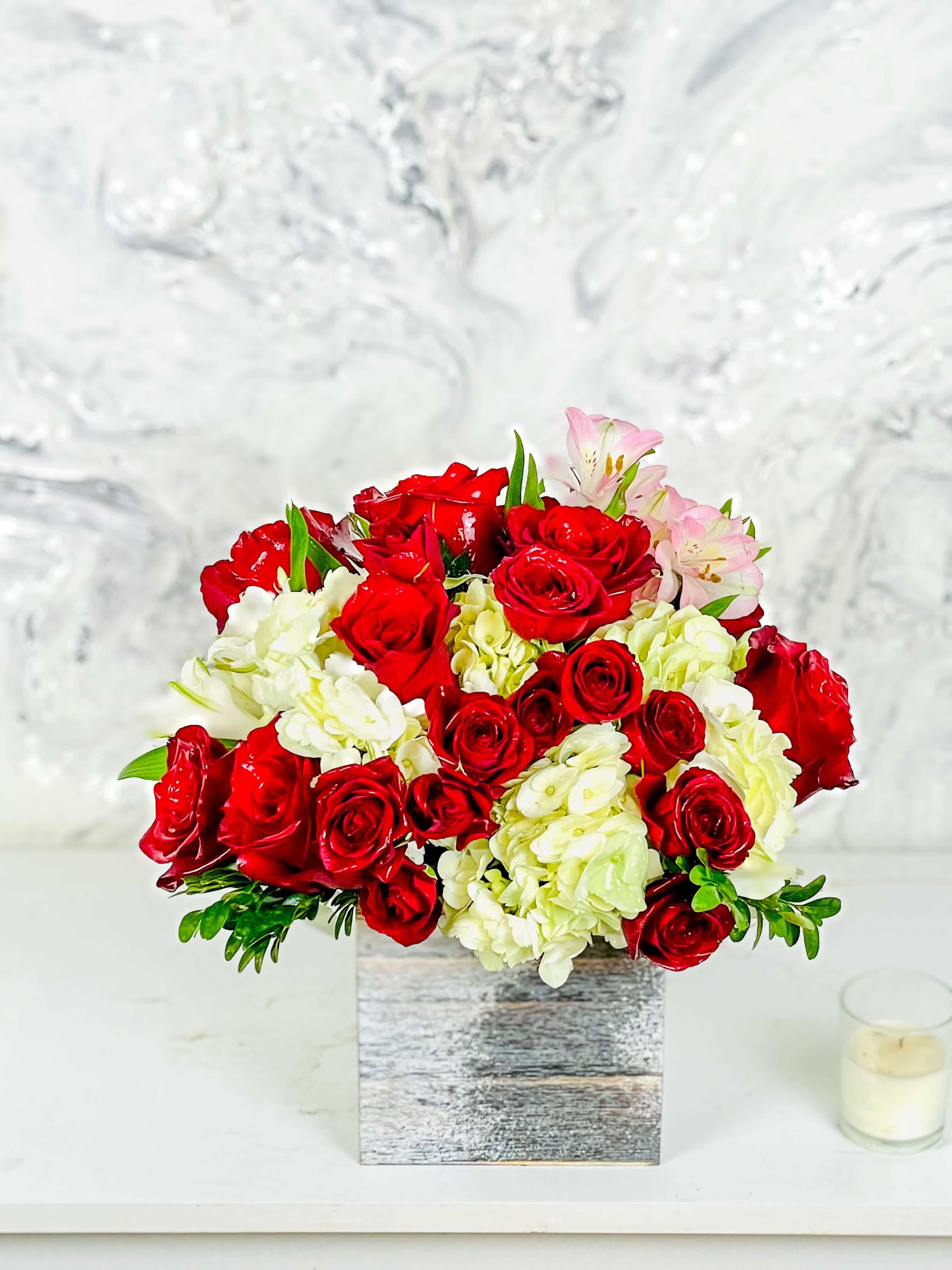 Red roses and white hydrangeas in a square wooden vase with pink lilies