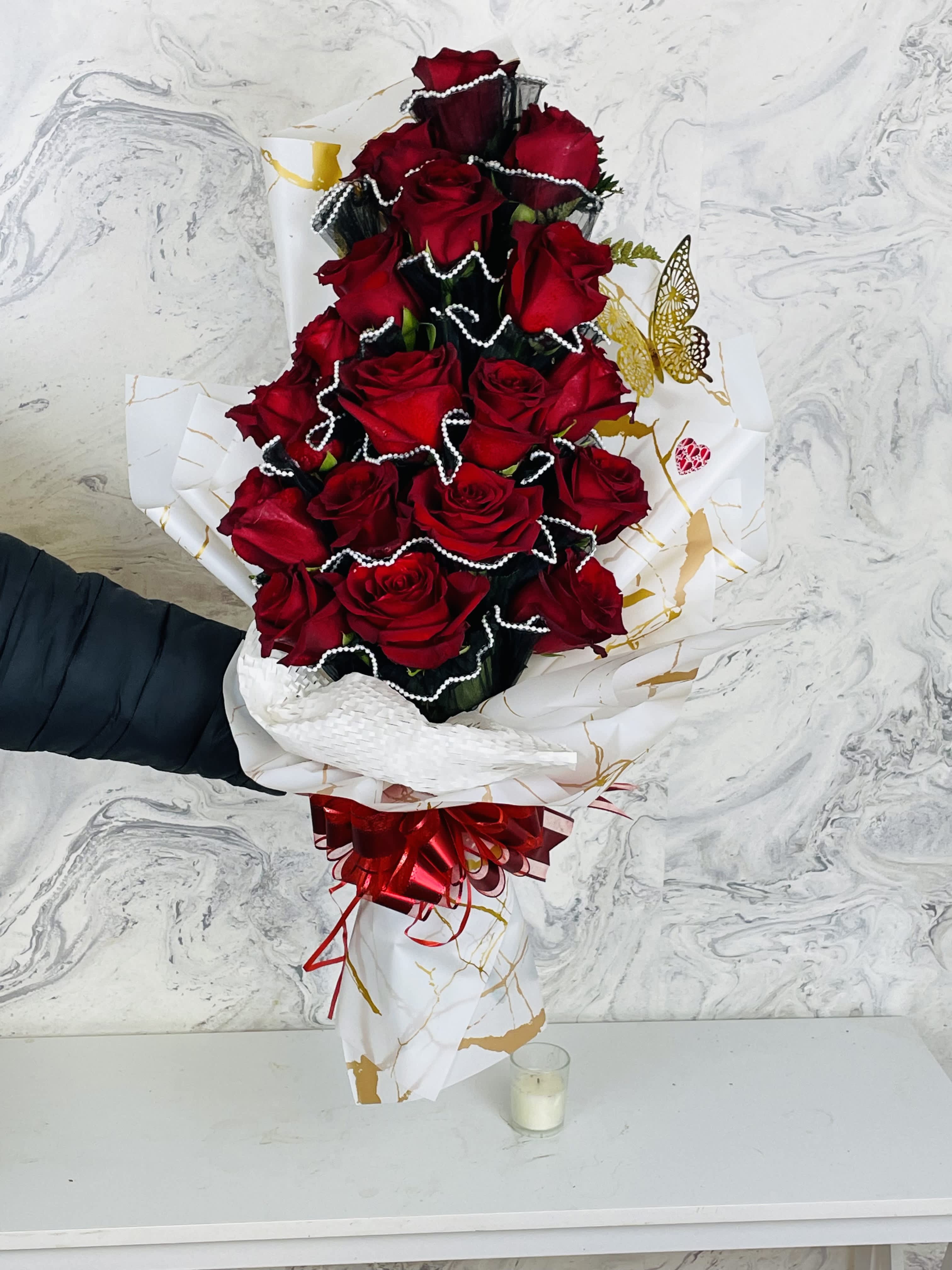 Tall bouquet of red roses wrapped in white paper with a red bow
