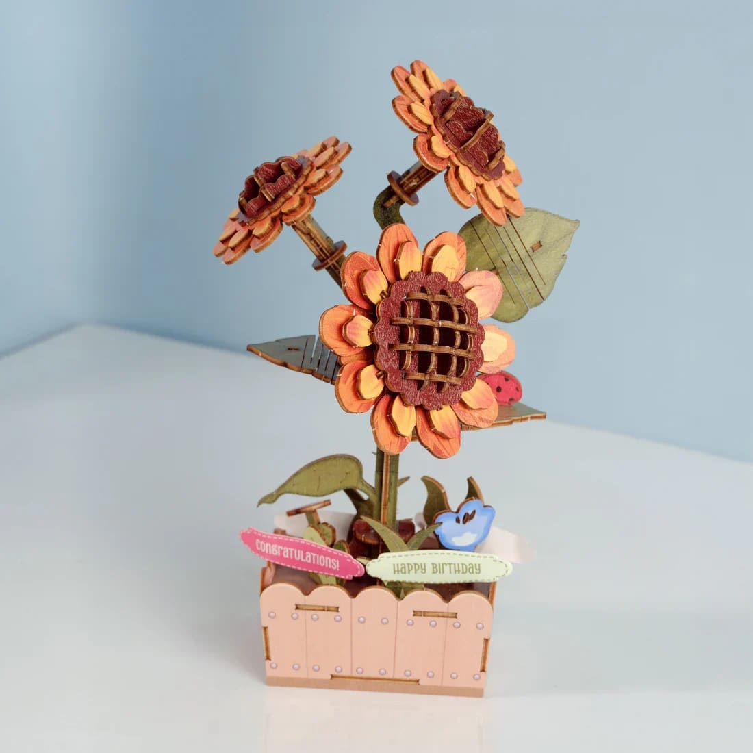 Hands Craft - Sunflower Wooden 3D Puzzle - Build a bright sunflower set in full bloom with this easy-to-assemble DIY wooden puzzle. Made from smooth wood, the precision-cut pieces fit together without glue or tools. The finished sunflower makes a cheerful decorative accent for desks or shelves. Perfect for puzzle lovers, craft enthusiasts, or anyone who enjoys a relaxing project, this sunflower set combines creativity, focus, and a rewarding final result.   The set also includes interchangeable message signs such as “I Love You,” “Happy Birthday,” “Congratulations,” and “Thank You,” allowing you to customize the display to suit the occasion and create a thoughtful, personal gift.  Age Range: 14+  Assembled Dimensions: 4.9 x 3.5 x 8.27 inches  Assembly Time: 2 hours  Piece Count: 115 pieces