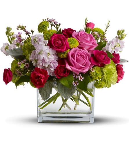 Pink and red roses in a clear glass vase with green and white accents