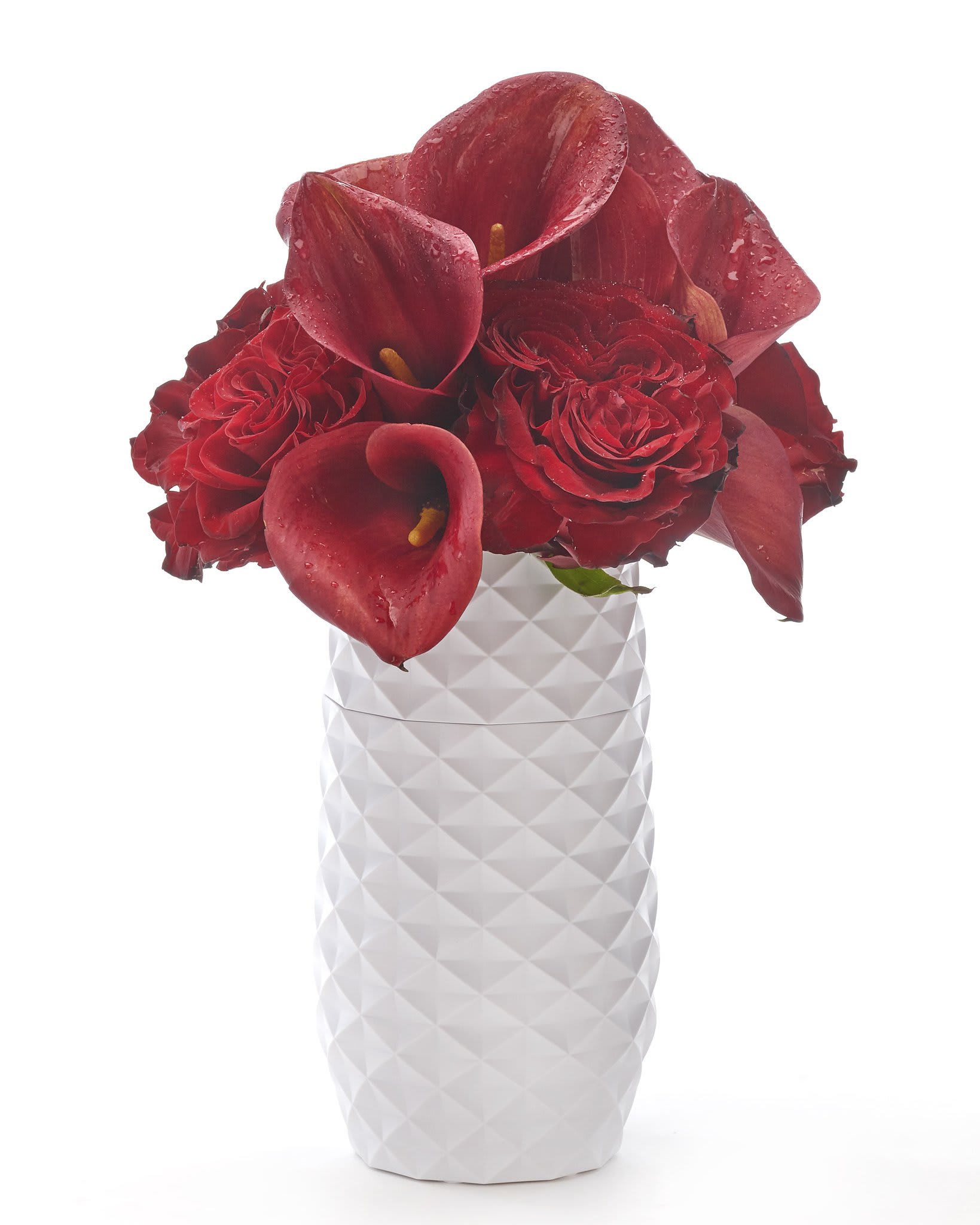 Red calla lilies and roses in a white textured vase