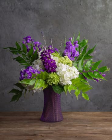 Purple and white floral arrangement in a purple vase