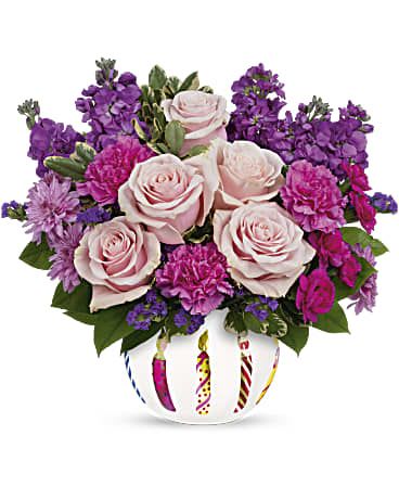 Pink roses and purple flowers arranged in a decorated white vase