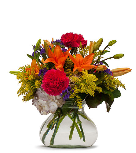 Colorful bouquet of lilies, carnations, and hydrangea in a clear glass vase