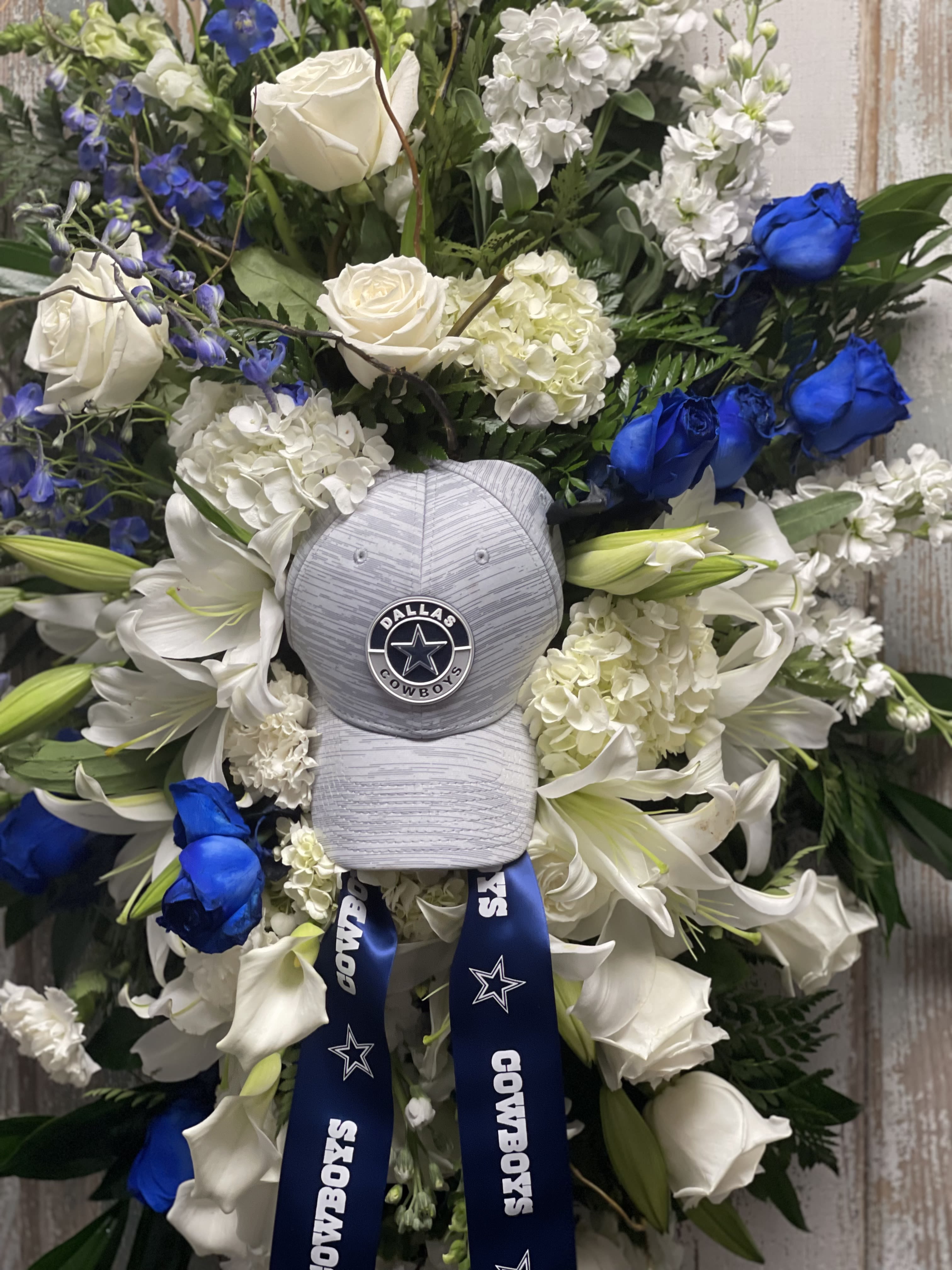 NFL Fan Tribute Standing Spray - This Standing Spray pays tribute to a devoted football enthusiast with fresh seasonal flowers arranged around a football themed keepsake.