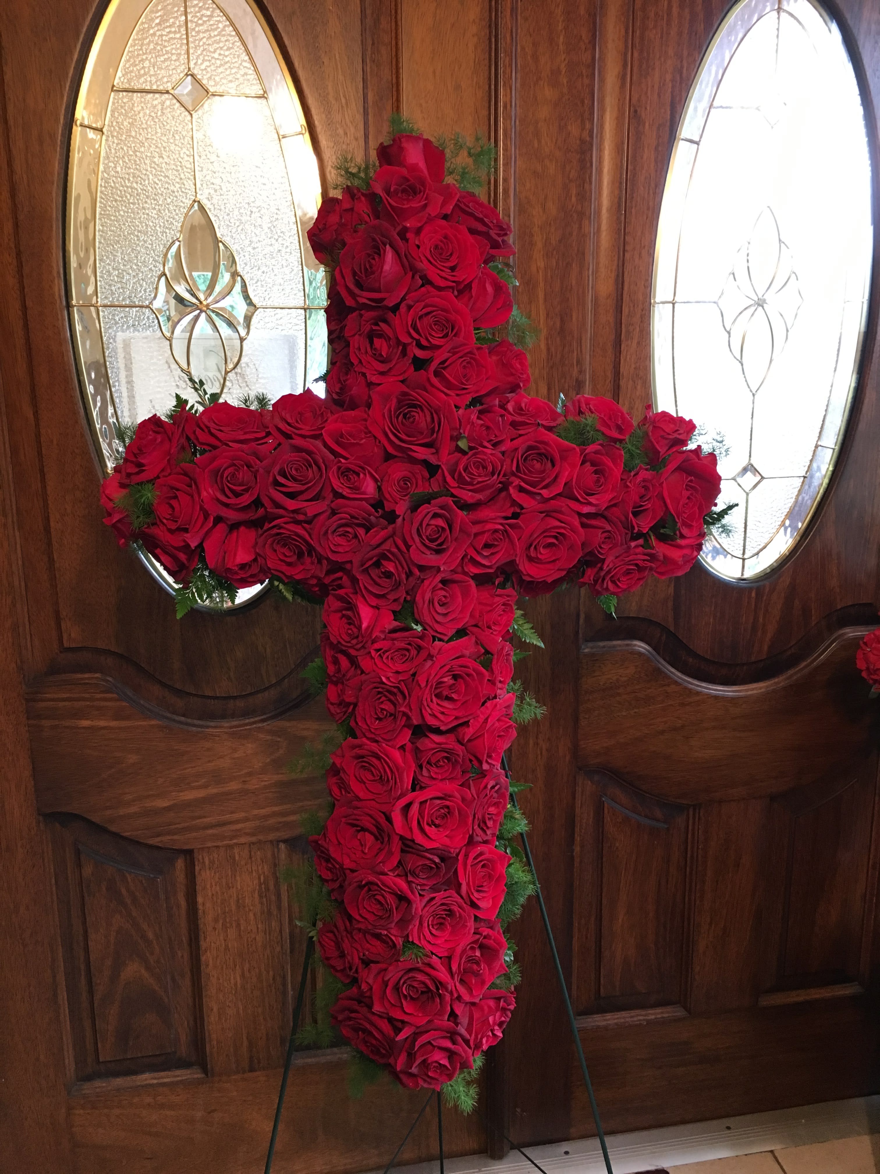 Cross-shaped arrangement of red roses on a stand