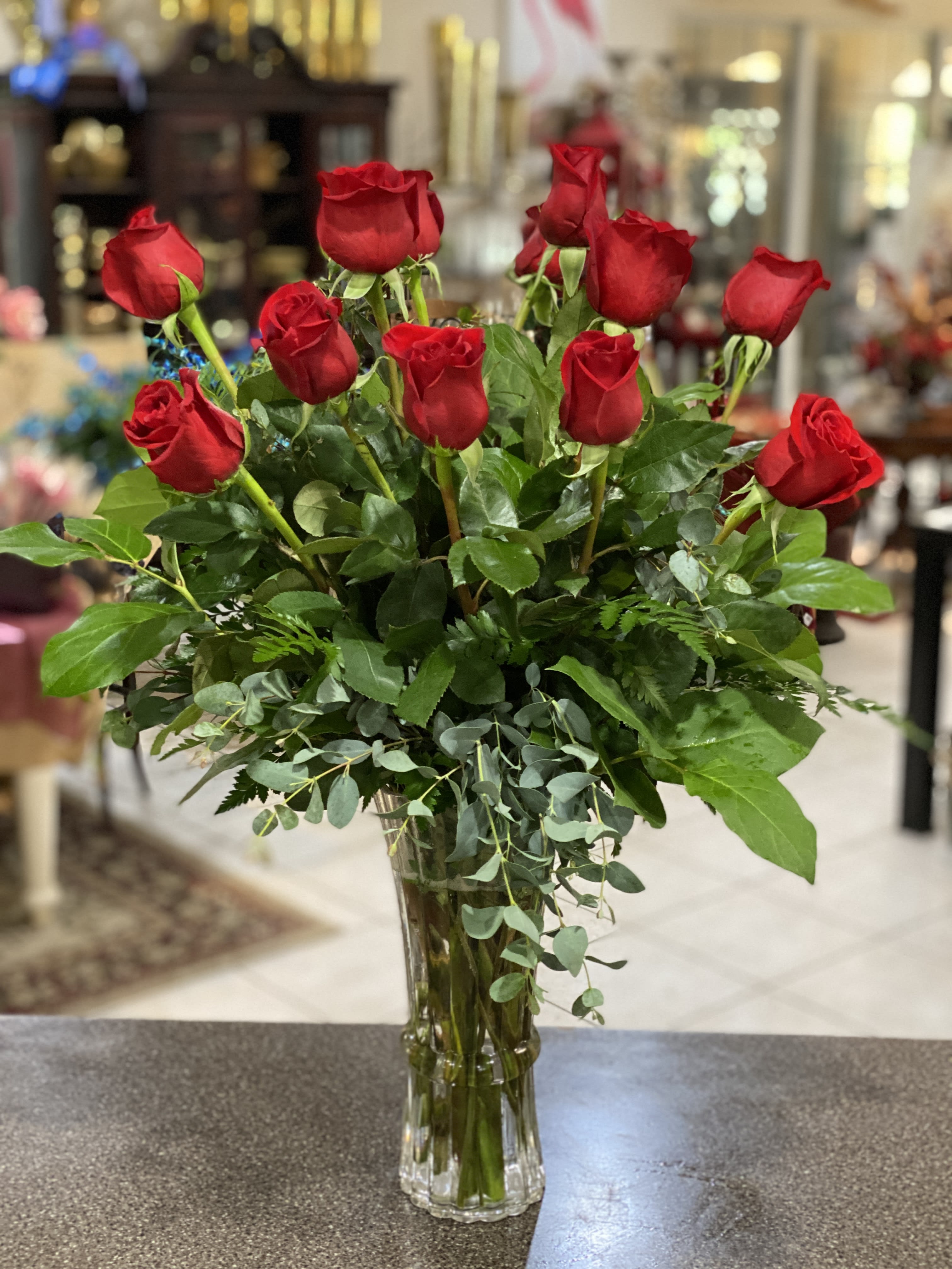 Red roses arranged in a clear glass vase with mixed greenery