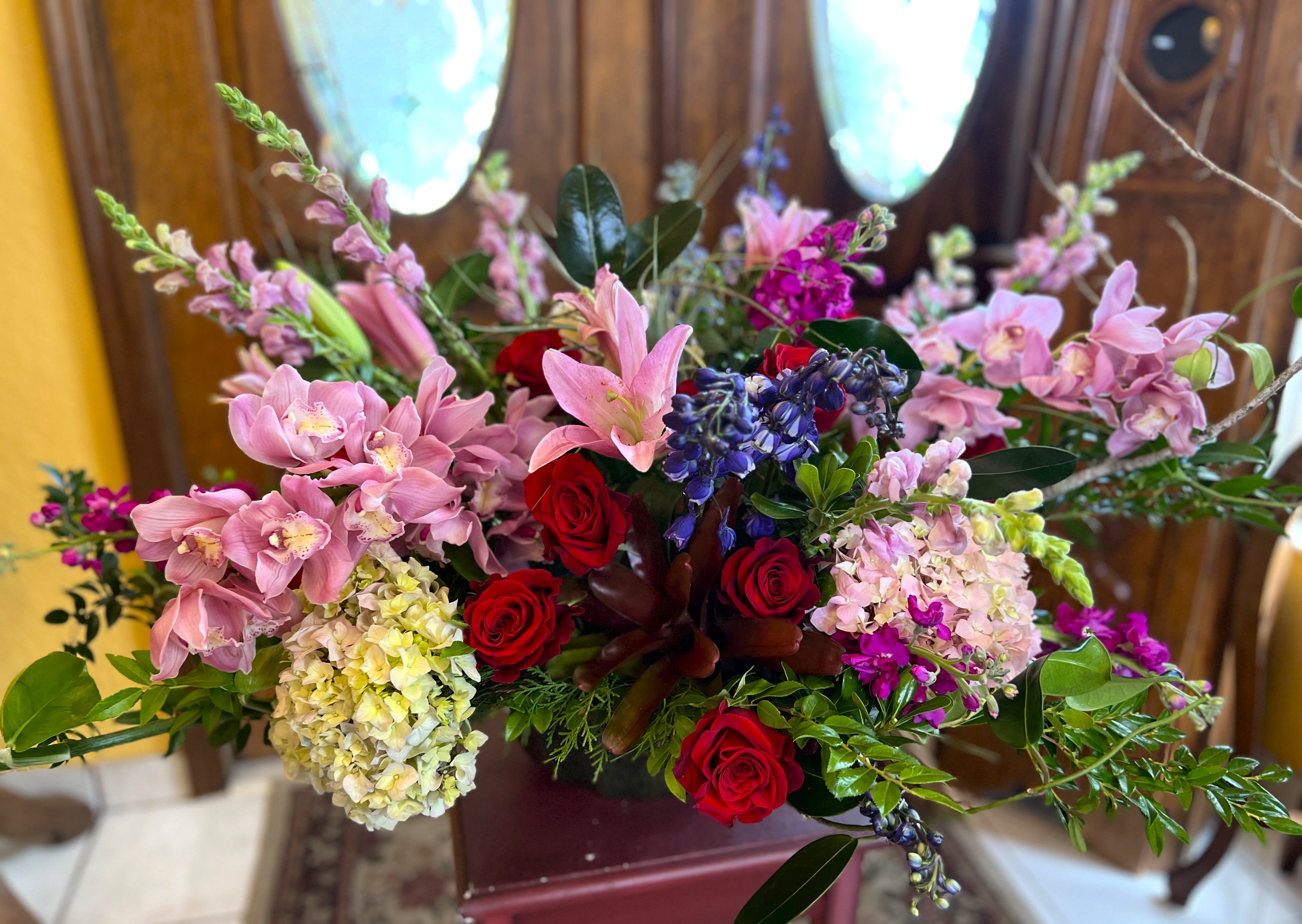 Mixed bouquet with pink orchids, red roses, and blue flowers in a vase