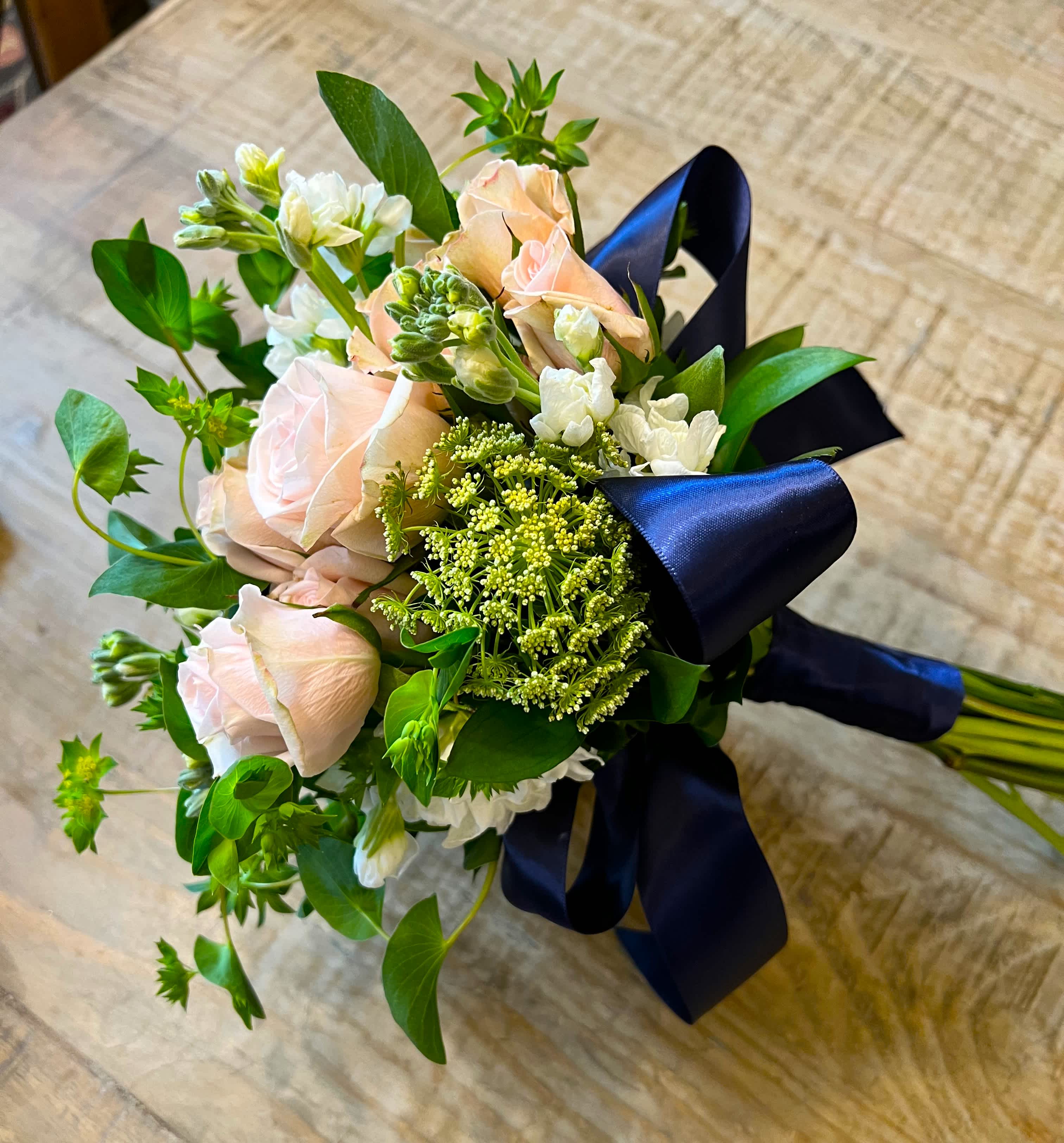 Bouquet of pale pink roses and white flowers tied with a dark blue ribbon