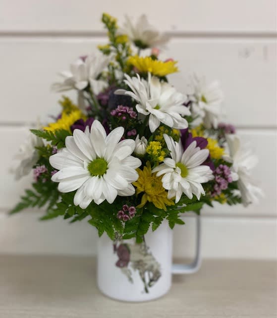 White and yellow daisy bouquet in a white mug