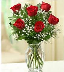 Bouquet of red roses and baby's breath in a clear glass vase