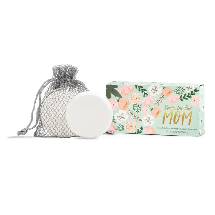 A mesh bag with a white shower steamer beside a floral gift box.