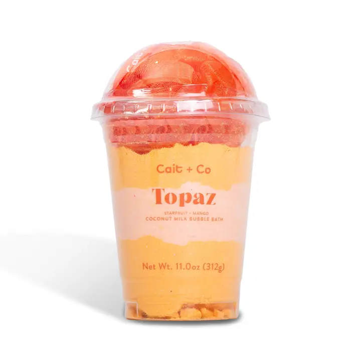 Orange bath product in a clear plastic cup with a domed lid