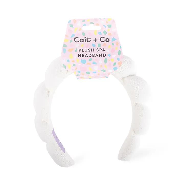 White plush spa headband with a pastel patterned tag
