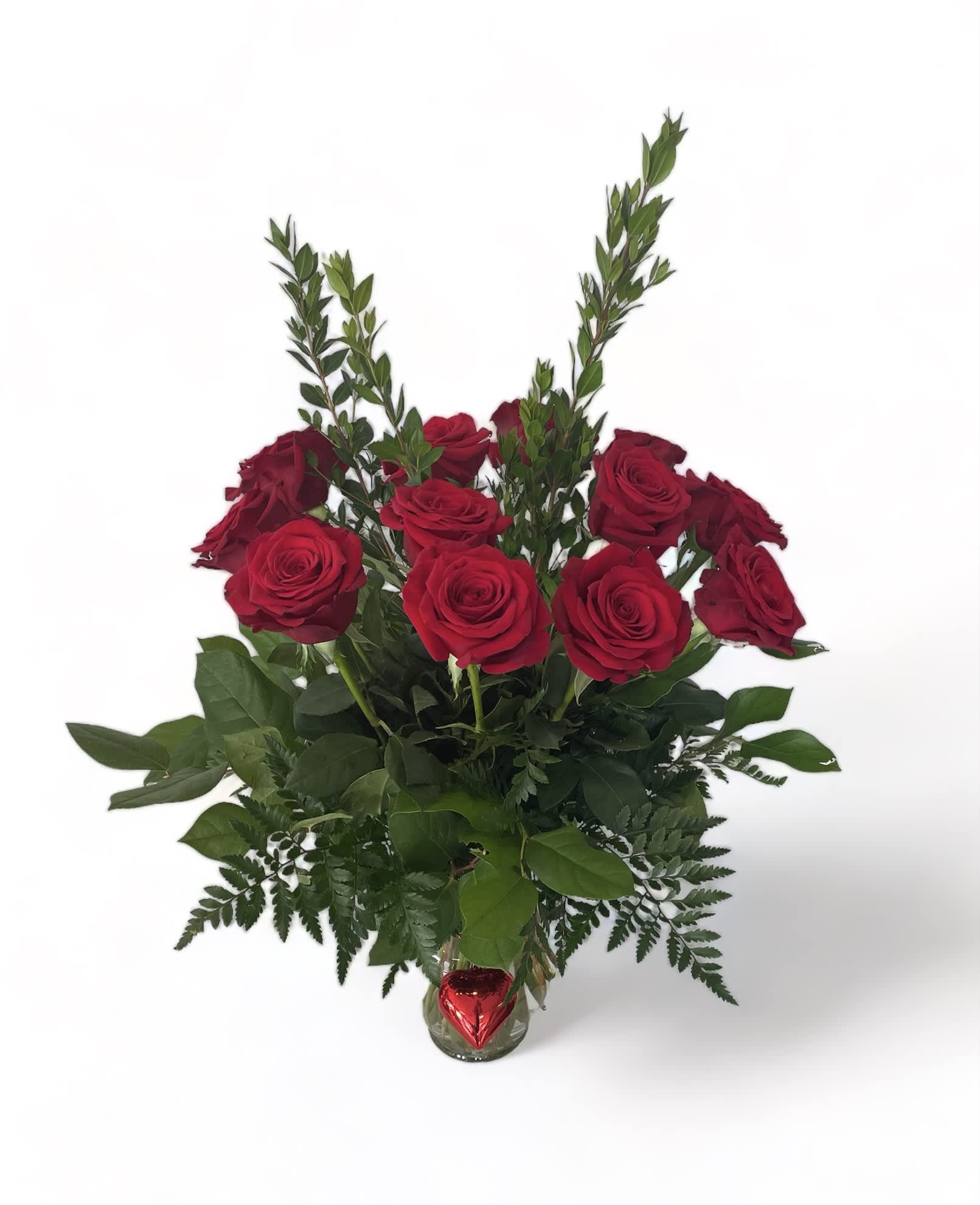Red roses arranged in a clear glass vase with a red heart ornament