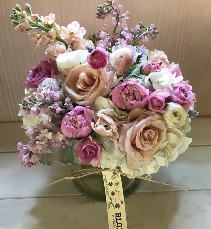 The Billie - A violet, pale pink pastel arrangement with the finest colors and flowers. Very feminine and pretty arrangement placed in a clear vase 5 by 5", full of lovely pale purple, nude and blush colors. Roses of the prettiest pastels mixed with seasonal garden like flowers such as lilacs, sweet peas, anemones, peonies, dahlias or other beautiful flowers (varies according to season). Blomst LA only uses fresh, high quality flowers, all carefully selected every day to fit your flower order. We offer a personal hand delivery by our own delivery staff and guarantee the flowers will look perfect, when they arrive. We deliver in Glendale, Pasadena, Eagle Rock, Hollywood, Burbank, Beverly Hills - and everywhere else in Greater Los Angeles.