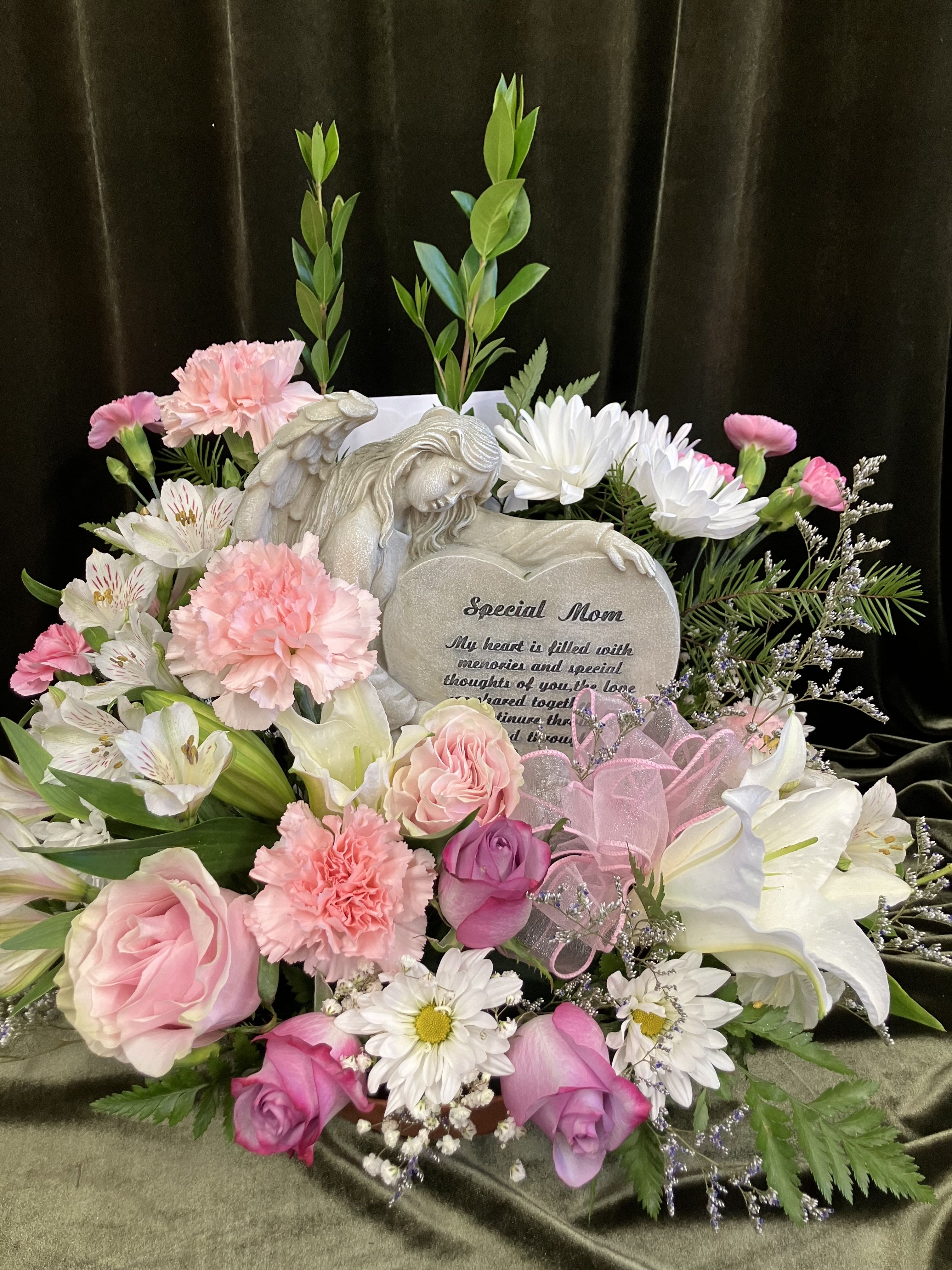 Pink and white floral arrangement with a memorial plaque and angel figurine