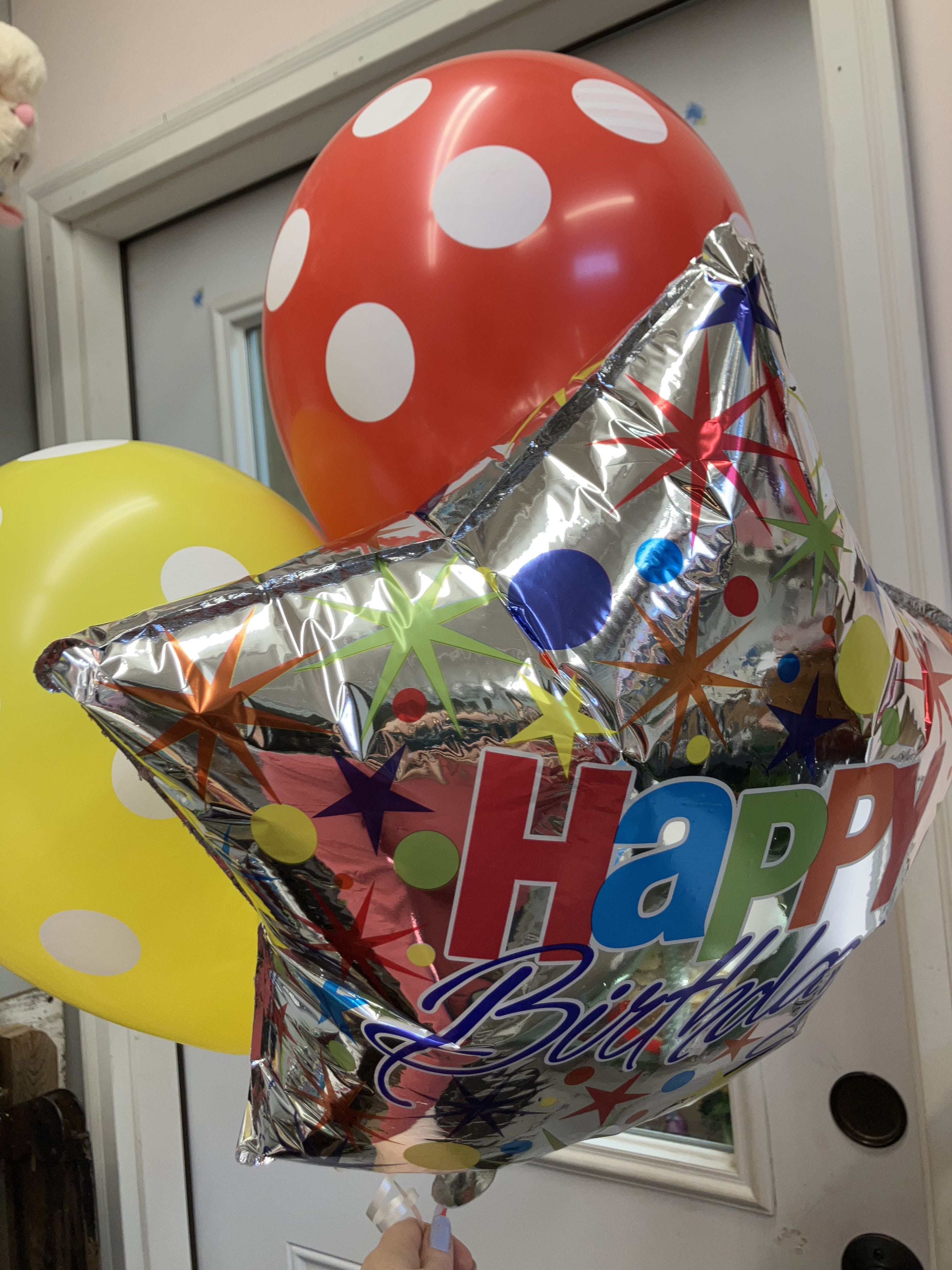 Birthday balloons including a silver star and red and yellow polka-dot balloons