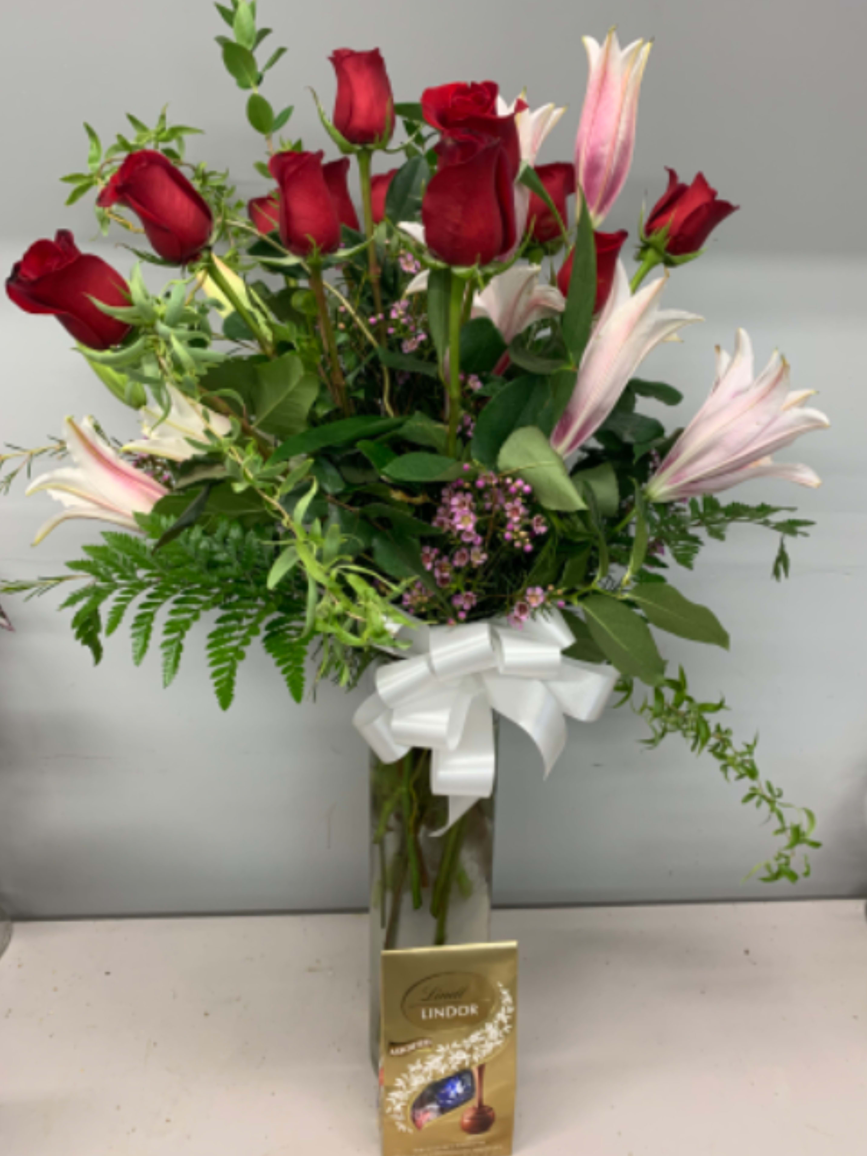 Make a Statement Dozen Red Roses - Knock her socks off with a  special arrangement of a dozen red roses, stargazer lilies and filler in a cylinder vase with chocolates  