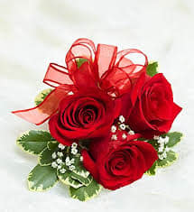 Small cluster of red roses with white filler flowers and a red ribbon bow.