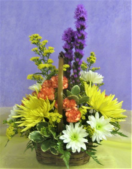 Basket arrangement with yellow, white, orange, and purple flowers