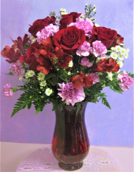 Red roses and pink carnations in a dark glass vase