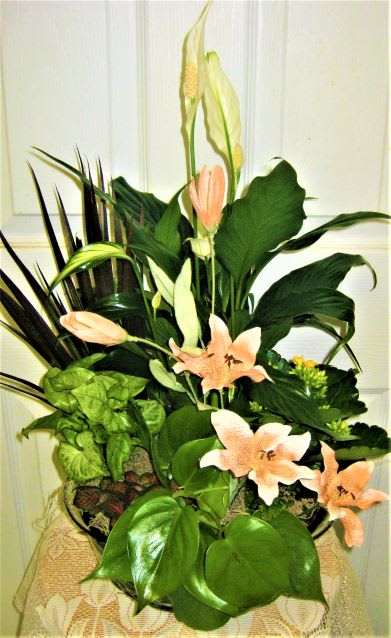 Tall floral arrangement with peach lilies and large green leaves