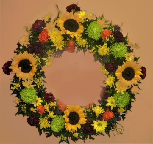 Circular floral wreath with sunflowers, roses, and mums