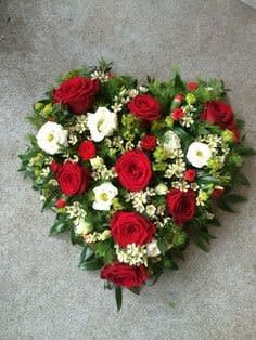 Heart-shaped bouquet of red and white flowers on a gray surface