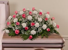 Pink and white floral casket spray with greenery