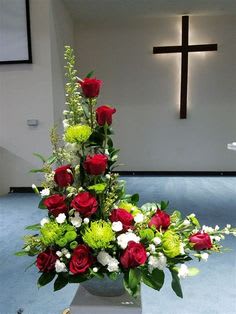 Tall floral arrangement with red roses and green accents in a church setting