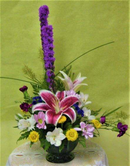 Mixed floral arrangement with pink lilies and purple flowers in a vase