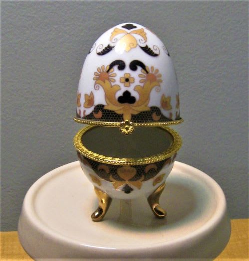 Decorative egg-shaped trinket box with gold trim on a round stand