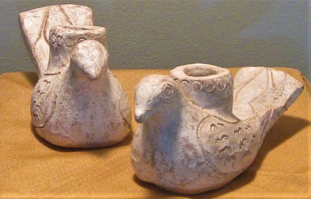Two bird-shaped ceramic candle holders on a gold cloth