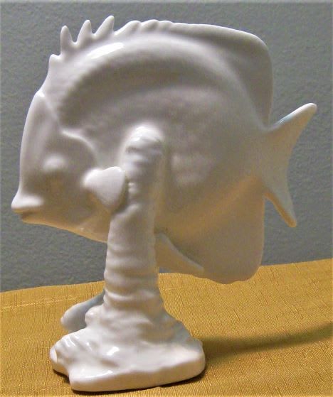 White ceramic fish-shaped figurine on a yellow surface