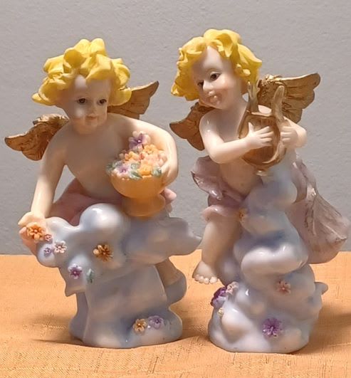 Two cherub figurines holding flower-filled bowls