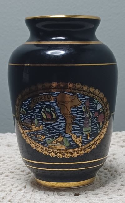 Black decorative urn with gold trim and a colorful emblem