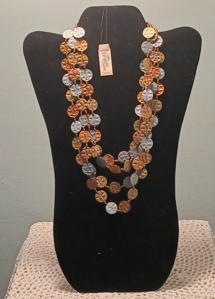 Layered coin necklace on a black display bust