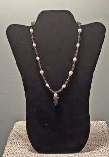 Beaded necklace displayed on a black bust stand
