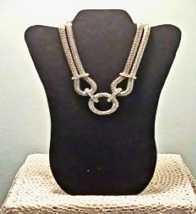 Silver necklace displayed on a black bust stand