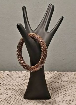Black hand-shaped display holding a braided bracelet