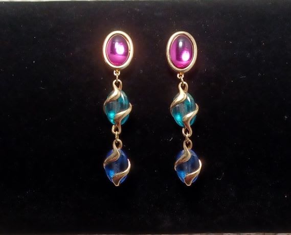 Pair of dangling earrings with pink and blue beads on a black background