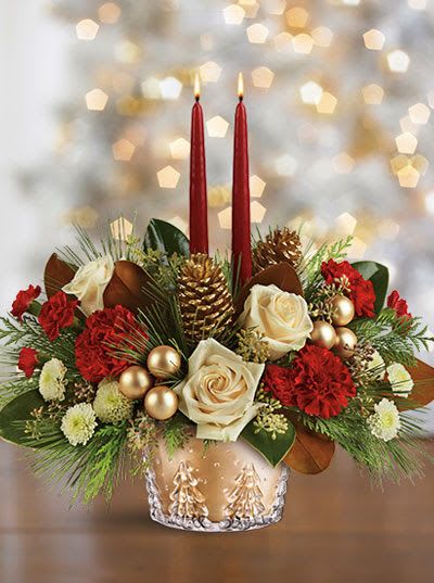 Holiday centerpiece with red candles, white roses, and pinecones in a gold vase
