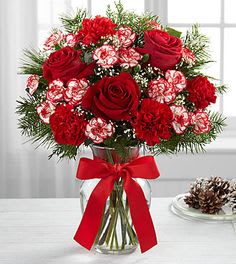 Red roses and carnations in a glass vase with a red ribbon