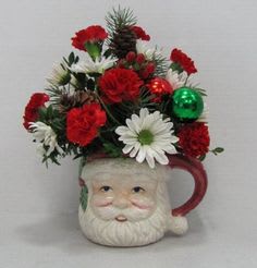 Santa mug filled with red and white flowers and holiday ornaments