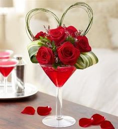 Red roses arranged in a martini glass with heart-shaped wire handles
