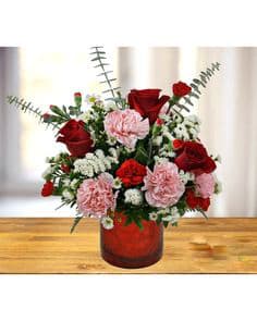 Red roses and pink carnations in a red glass vase