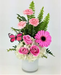 Pink roses and carnations in a white vase with a butterfly accent